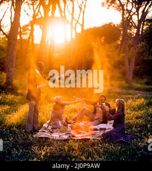 Vintage Italy 1970s, 2 couples of cheerful friends having a picnic at sunset, solar light flare, late afternoon, Roman countryside, Lazio, Europe, Stock Photo