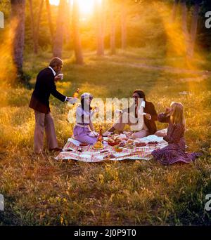 Vintage Italy 1970s, 2 couples of cheerful friends having a picnic at sunset, solar light flare, late afternoon, Roman countryside, Lazio, Europe, Stock Photo