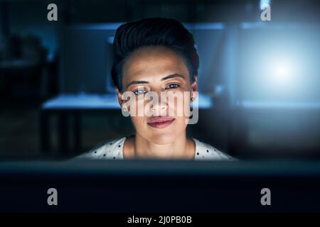 Being tired is part of the job. Shot of a tired young female programmer working on a computer in the office at work during the night. Stock Photo