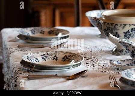 Porcelain tableware. Table service set on the table. Old plates and spoons. An elegantly set table. Stock Photo