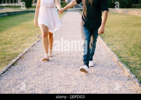 Man and woman walking along the gravel path in the park holding hands Stock Photo