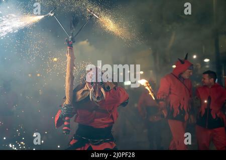 A person dressed as a demon holds firecrackers during the Parade of ...