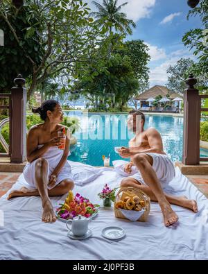 Couple breakfast by the pool , man and woman on vacation in Thailand having breakfast by pool Stock Photo