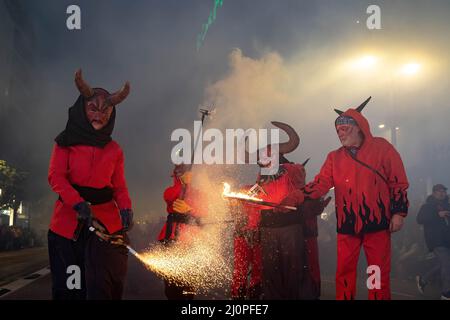 Several people dressed as demons light firecrackers during the Parade ...