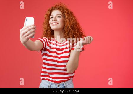 Cute pleased happy good-looking redhead ginger girl curly hairstyle smiling perfect toothy grin posing delighted amused hold sma Stock Photo