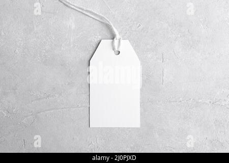 Rectangle white tag mockup with white cord, close up. Blank paper rectangular price tag mockup isolated on grey background with copy space, Sale and B Stock Photo