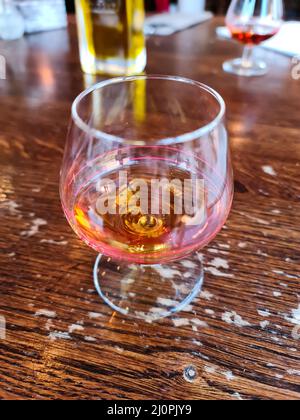 A glass of amaretto with soft background on a wooden table Stock Photo