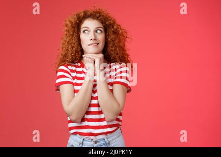 Cheerful intrigued redhead silly curly-haired woman smiling interested hold hands chin face-line imaging thinking about tasty bu Stock Photo