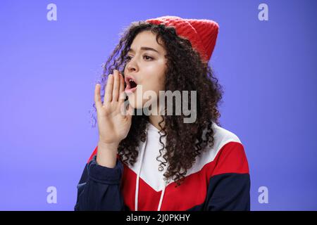 Portrait of worried sister calling sibling outdoors open mouth looking left seriously and holding palm near lips as shouting nam Stock Photo