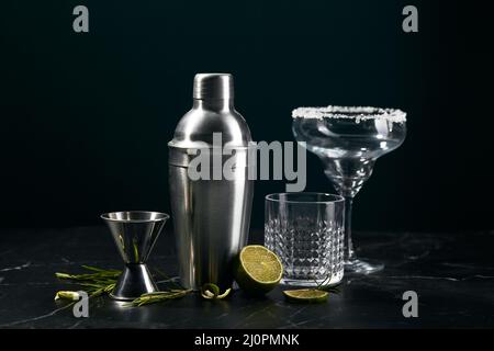 Cocktail shaker and cocktail glasses, and ingredients on dark marble background Stock Photo
