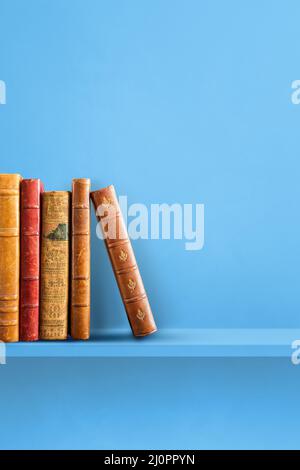 Row of old books on blue shelf. Vertical background Stock Photo