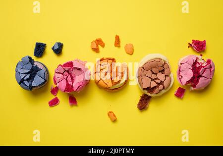 Broken round macarons with crumbs on a yellow background, delicious dessert Stock Photo