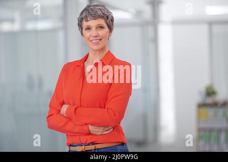 Its passion and commitment that drives my business. Portrait of a mature businesswoman standing with her arms crossed in an office setting. Stock Photo