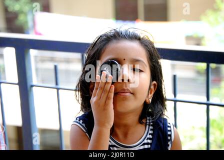 Young Asian kid closing one eye with lens cap Stock Photo