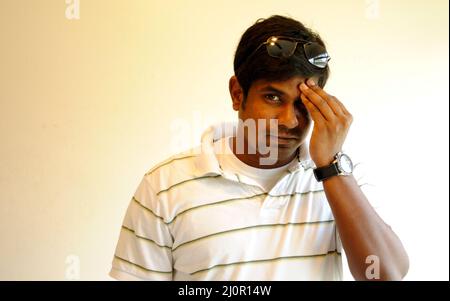 Indian male posing with a hand on a eye with sun glass with a white background Stock Photo