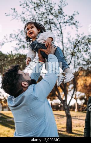 Proud father throws his little daughter in the air who laughs happily. Stock Photo
