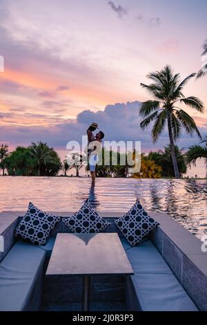 couple watching the sunset in an infinity pool on a luxury vacation in ...