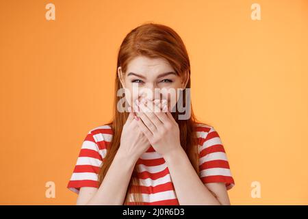 Haha very funny. Silly tender cheerful redhead girl laughing, giggle hilarious joke, cover mouth press palms lips chuckling sile Stock Photo