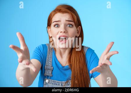 Close-up uneasy disappointed cute gloomy redhead girl, raise hands dismay full dibelief, frowning gasping upset, losing competit Stock Photo