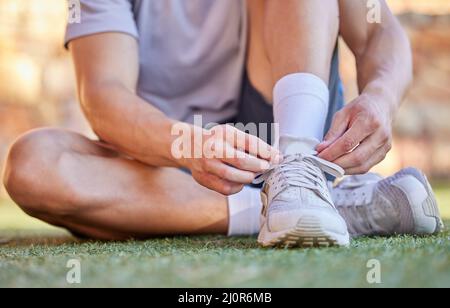 You dont want your shoes slipping off. Shot of an unrecognizable man tying the laces of his running shoes. Stock Photo