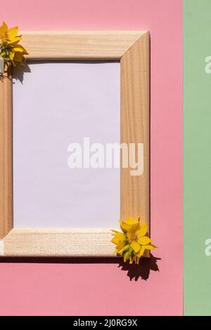 photo frame decorated with green leaves and orchid flowers on pink pastel background. empty space for text. Stock Photo