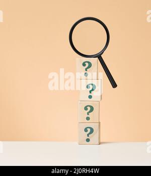 Wooden magnifying glass and question marks. The concept of finding an answer to questions