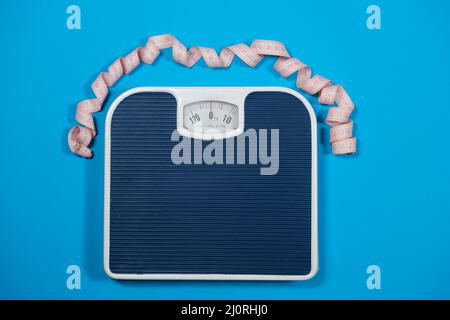 Floor scales and centimeter measuring tape on a blue background, top view. The concept of weight loss and weight control Stock Photo