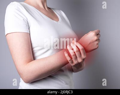 Woman suffering from wrist pain. Hand holding painful wrist with red point closeup. Health problems. Injury, office syndrome concept. High quality photo Stock Photo