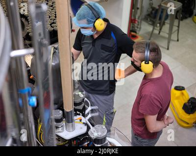 Workers wearing mask checking the machinery of a craft beer factory. Stock Photo