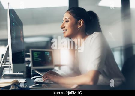Life as a coder. Shot of a woman using a computer in a modern office. Stock Photo
