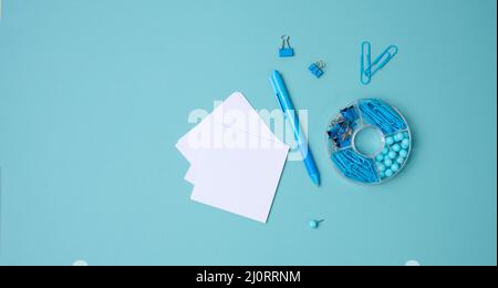 Stack of white square sheets of paper for notes, stationery on blue background, top view Stock Photo