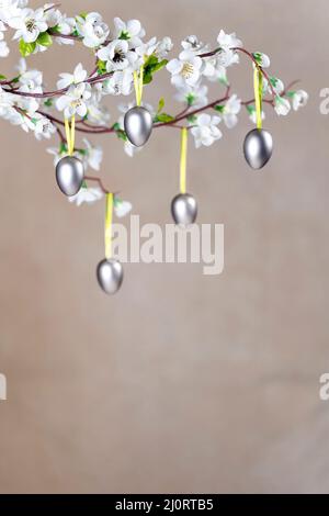 Silver Colored Easter eggs hanging on branch with white flowers Stock Photo