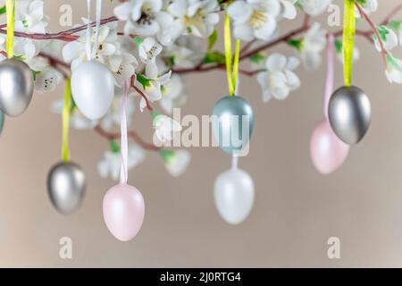 Colored Easter eggs hanging on branch with white flowers Stock Photo