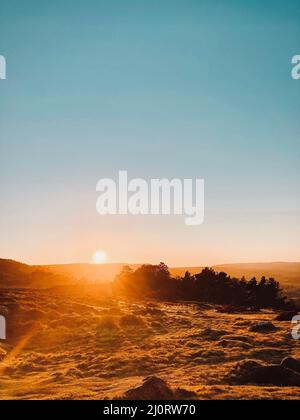 Sunsetting on the horizon at sunset over Ilkley Moor viewed from the Cow and Calf in Ilkley, West Yorkshire. Stock Photo