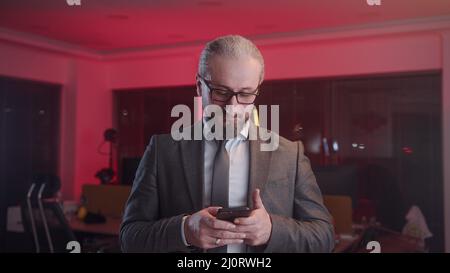 Middle aged scholar businessman with glasses using smartphone he making payment or using app Stock Photo