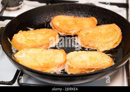 The process of frying bread croutons in an egg in a cast-iron skillet Stock Photo