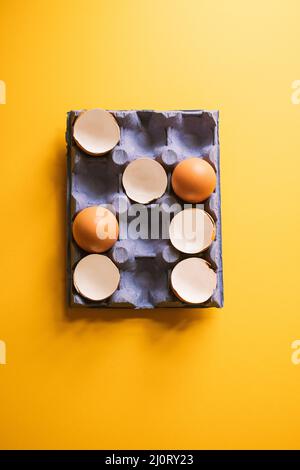 Egg shells and whole eggs in a carton. Top view. Stock Photo