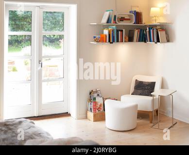 A homely and stylish space. An empty living room complete with an armchair and bookcase. Stock Photo