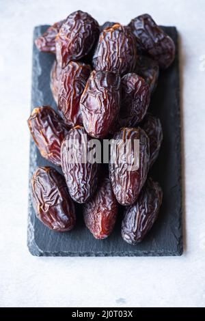 Medjoul dates on a black slate board on a gray background. Stock Photo