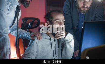 Three male colleague workers collaborating in office talking while looking at computer screen together at workplace. Office concept Stock Photo
