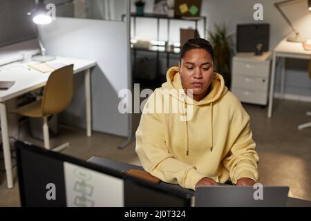 Portrait of female IT developer using computers while working in office at night, copy space Stock Photo
