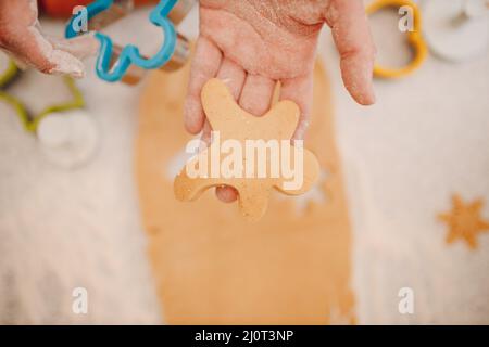 Woman hands form molds cutters ginger dough and makes delicious christmas ginger cookies. Cooking and decorating christmas desse Stock Photo