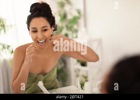 Young brunette woman cleaning teeth with dental floss near mirror at home, copy space. Oral hygiene, healthy lifestyle Stock Photo
