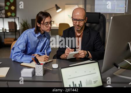 Portrait of two entrepreneurs collaborating during meeting while working in office at night Stock Photo