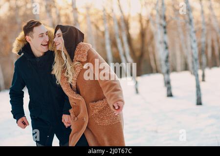 Loving young couple walking playing and having fun in winter forest park Stock Photo