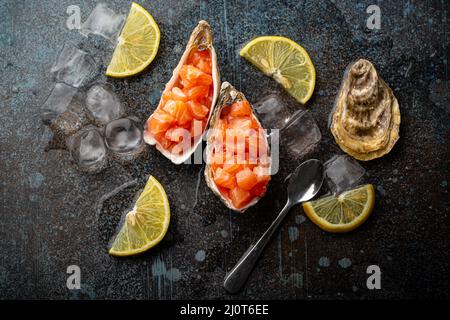 Salmon tartare raw chopped served in oyster shells top view on stone background Stock Photo