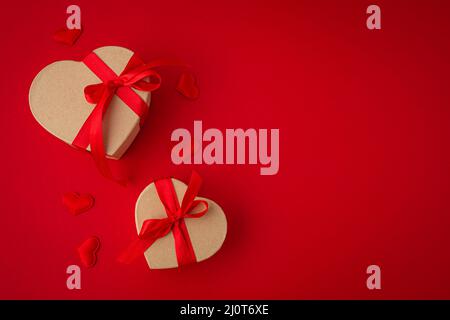 Two wrapped gift boxes in heart shape on red background, Saint Valentine Day Stock Photo