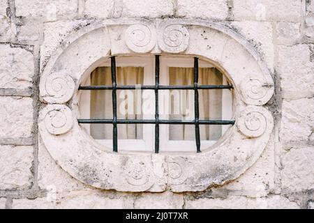 Small oval window in the pilaster on the old stone facade of the building Stock Photo