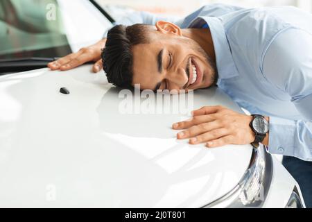 Happy young arab man hugging car of his dream Stock Photo
