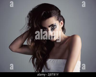 Makeup is an art and we can be artists. Studio shot of an attractive young woman wearing bold makeup. Stock Photo